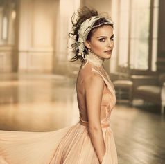 Natalie Portman in flowing peach dress, looking back in elegant room.