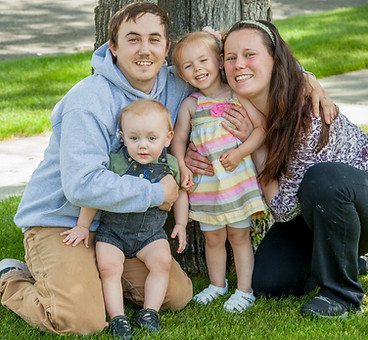 Family of four smiling in front of a tree