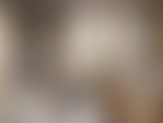 A bright, minimalist bathroom with a freestanding white soaking tub, walk-in shower, floating wood double vanity with white vessel sinks, gold fixtures, and a potted monstera plant.