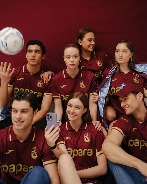 Six young people in sapra maroon jerseys posing with soccer ball.