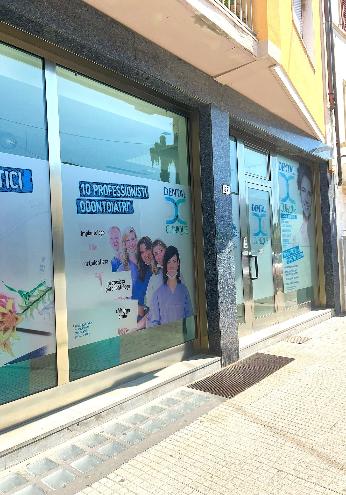 Vetrina di una clinica odontoiatrica con immagini pubblicitarie.