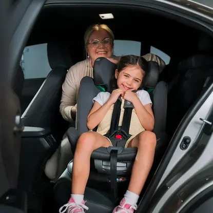 Pais colocando bebê em cadeirinha de carro giratória dentro do veículo