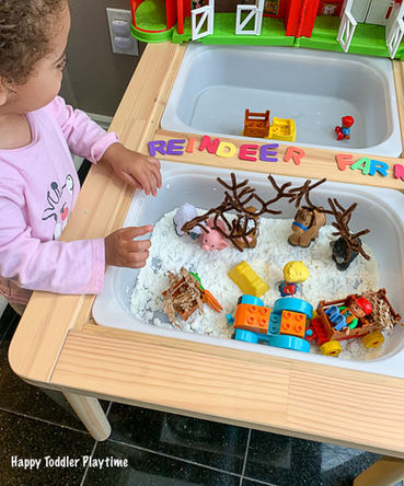 Bebê explorando diferentes texturas em mesa sensorial com materiais variados