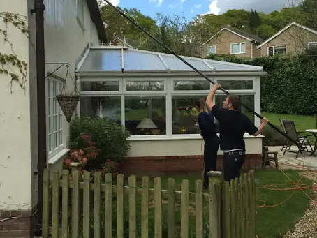 James cleaning windows with an extended window cleaning tool