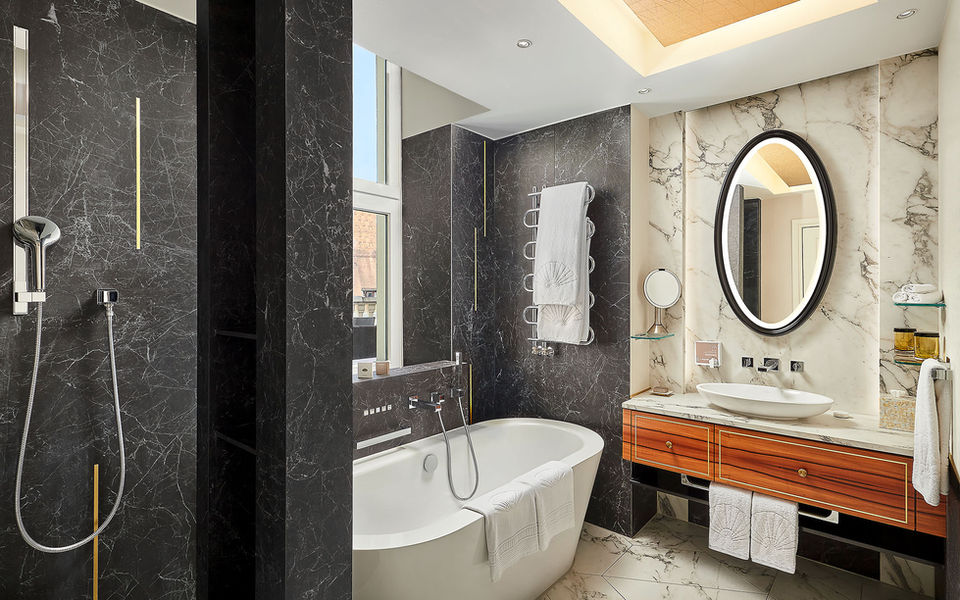 Badezimmer einer Suite im Mandarin Oriental München mit freistehender Badewanne und Marmorwänden