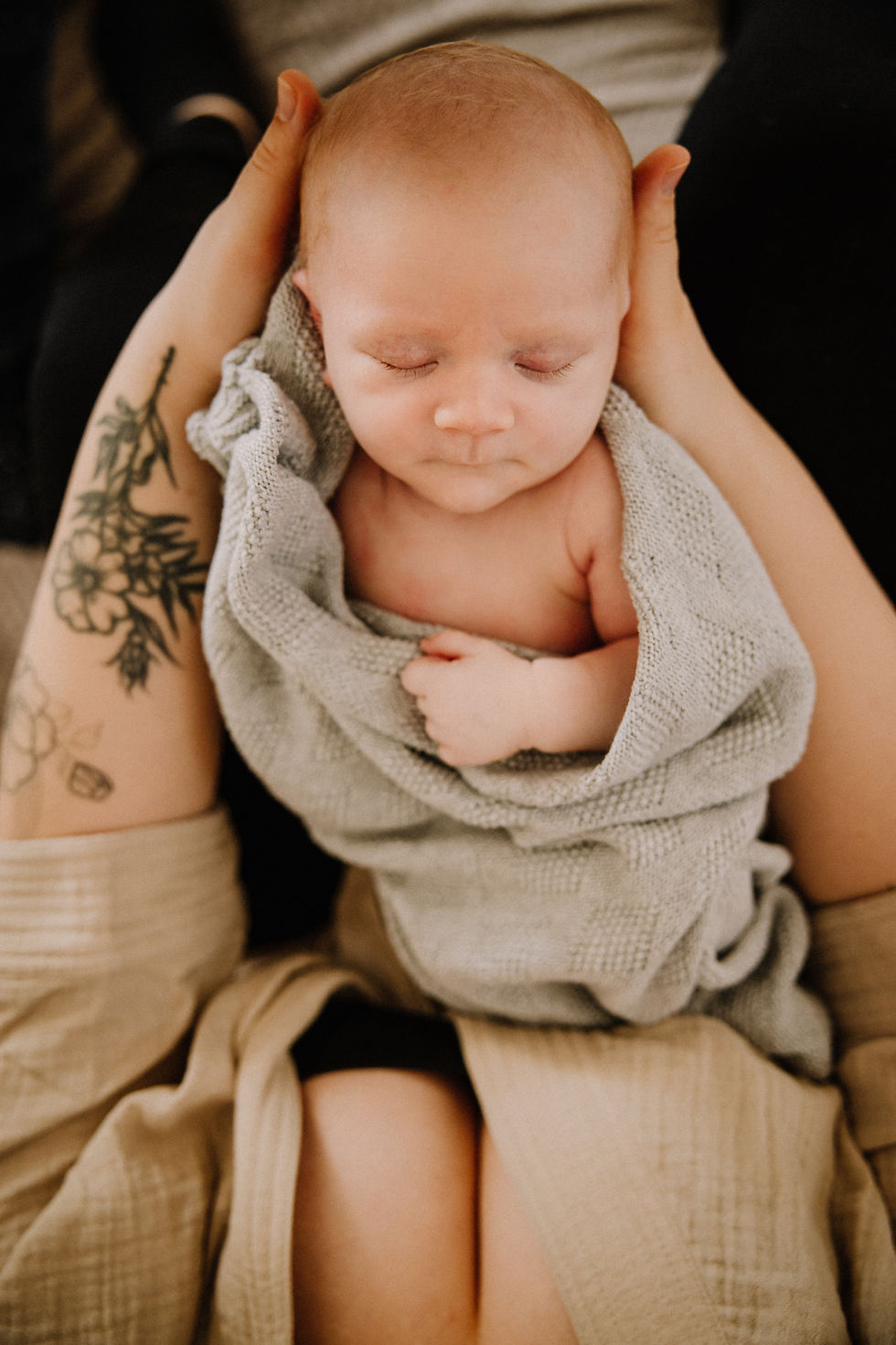 Neugeborenes wird zu Hause in den Armen gehalten – Familienshooting zu Hause in Marburg