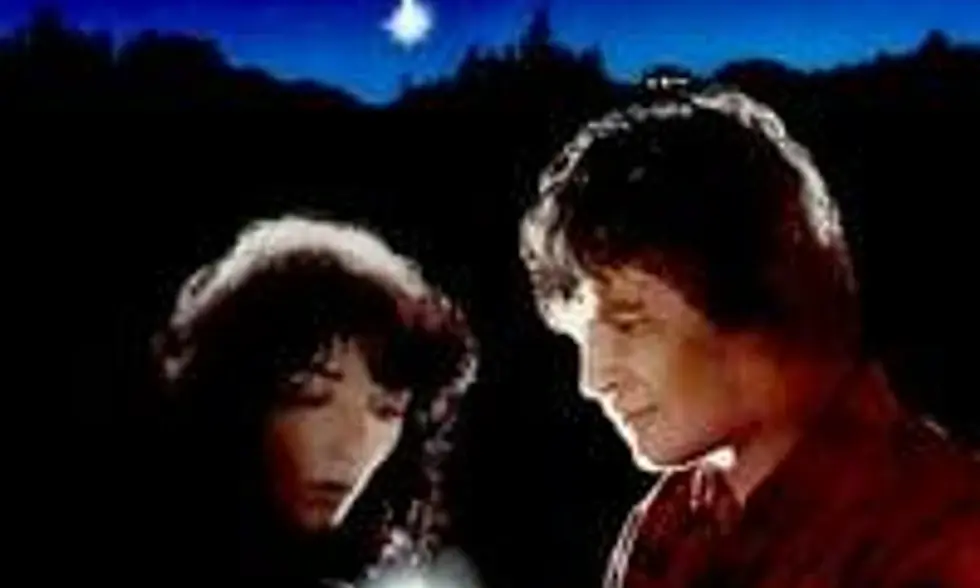 Karen Allan and Jeff Bridges, standing in darkness, looking down at something that glows.