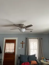 Silver ceiling fan in a living room with a wooden door
