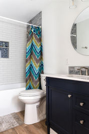 Modern bathroom with navy vanity and chevron curtain