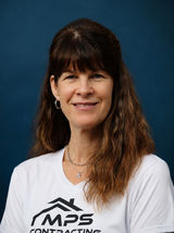 Carolyn smiling in a white MPS Contracting shirt with shoulder-length wavy hair against a blue studio background.