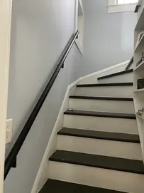 Modern white staircase with dark treads and black handrail