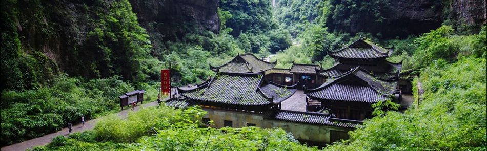 武隆天生三橋|映画『トランスフォーマー4』のロケ地として知られる、谷底に建つ伝統建築「天福官驛」を写した背景画像。武隆観光を象徴する人気スポットです。