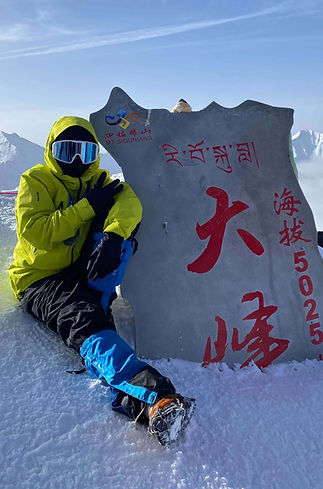 四川省・四姑娘山大峰（5,025m）に登頂した登山者が山頂標識の前で記念撮影。日本語ガイドと現地登山ガイドが同行する安心の四姑娘山登山ツアー