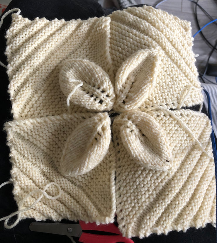 Four cream-coloured knitted squares, each with a diagonal leaf shape design which stands out slightly above the rest of the design. The leaves meet at the centre of the four squares.