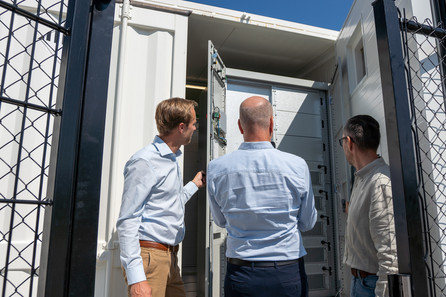 Three men look inside a battery storage unit