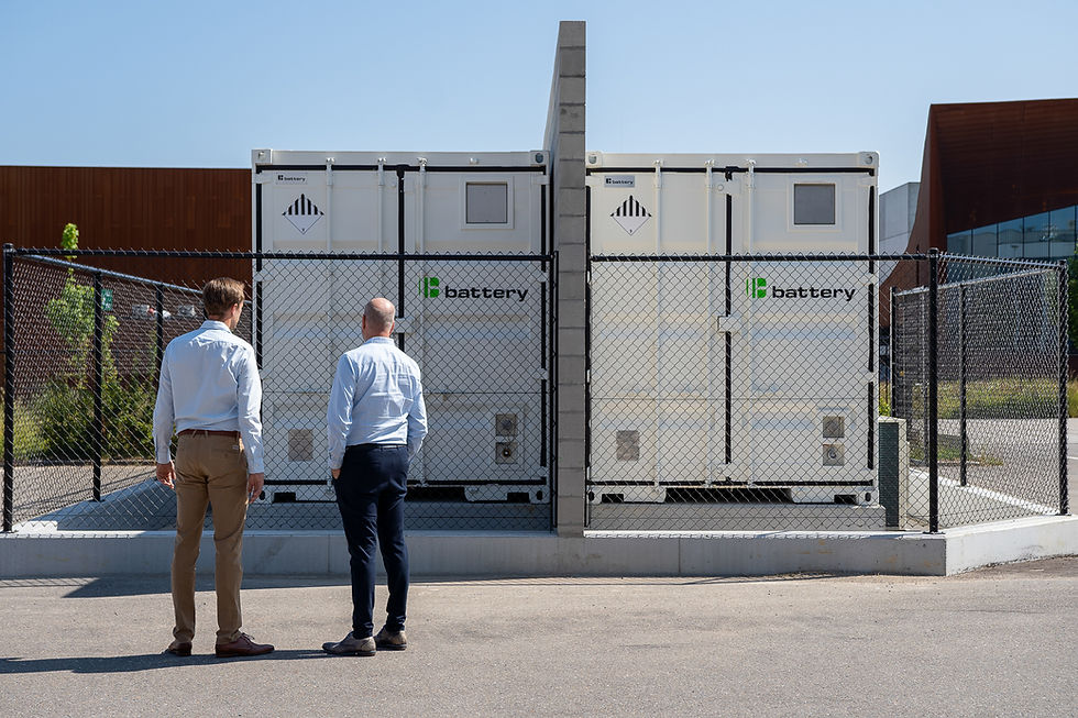 Two men stand by a fence looking at C-battery containers
