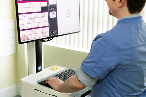 A trained medical professional reviewing a computer screen of a patient's moles.