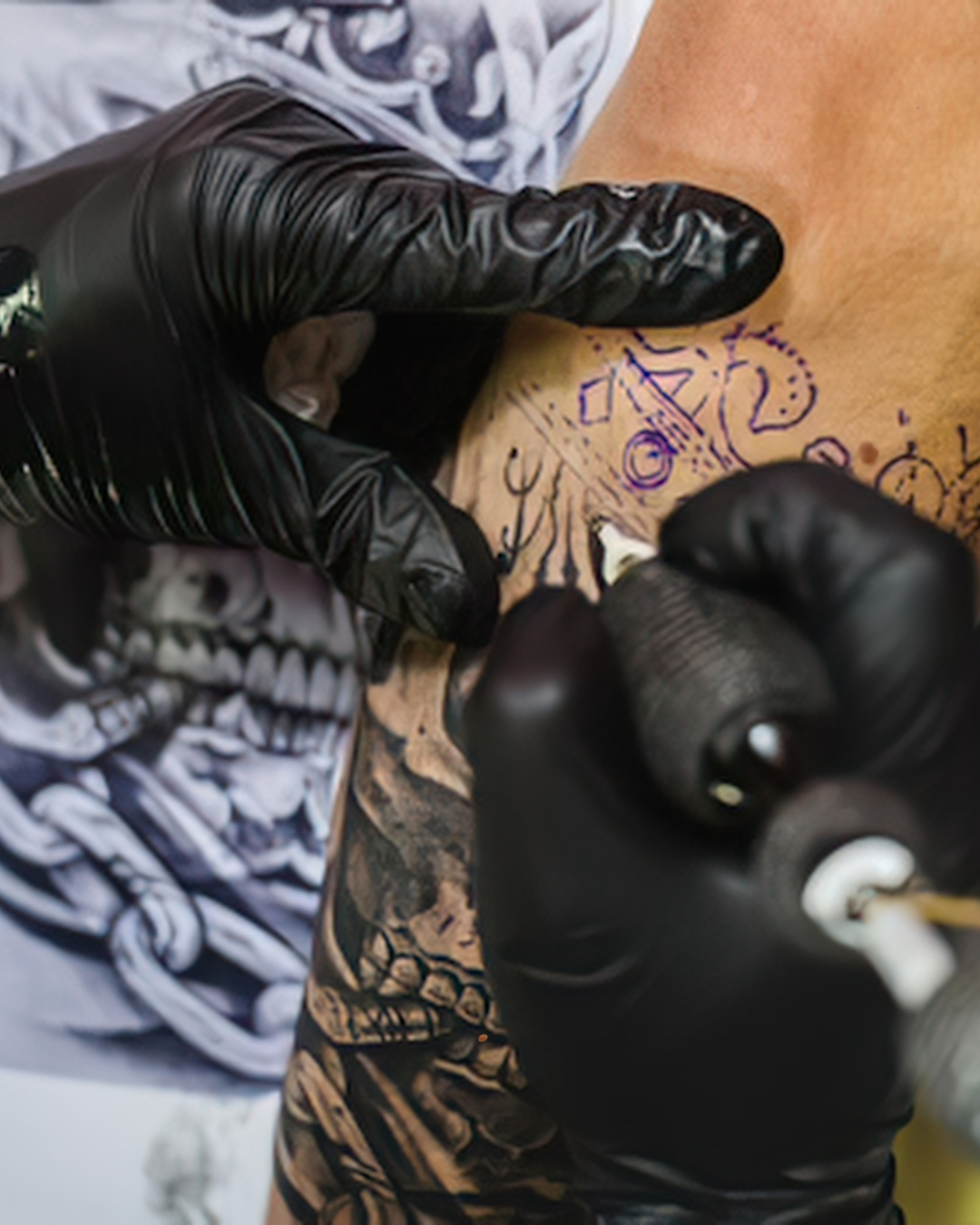 A close-up image of a tattoo artist giving someone a tattoo on their arm.