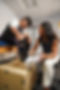 a woman and boy sitting together indoors. she is helping him adjust the Biomotum SPARK device that he is wearing on both legs