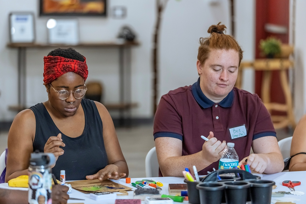 Two people focused on creating art during an arts-based session.