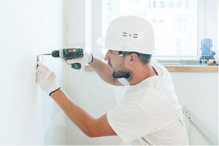An image of an electrician drilling a hole in a wall