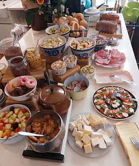 Gezellige brunchtafel met diverse ontbijtgerechten en verse producten in een kindvriendelijk café.