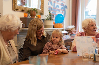 Drie vrouwen met een kind zitten in een kindercafé.