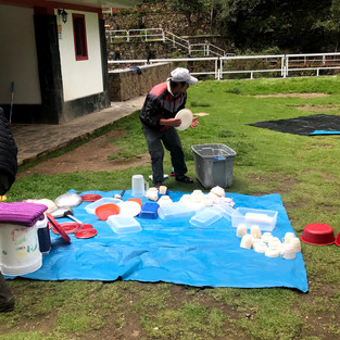 Porters cleaning tupperware on a blue tarp
