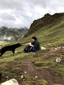 Woman offering a dog a piece of her sandwich amongst the mountains