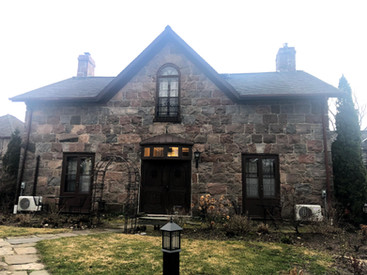 Stone house with three doors and one round window on the top of the middle door