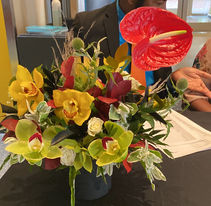 Beautifully arranged flower arrangement filled with yellow and green orchids with a red anthurium