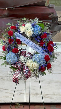 A red, white and blue wreaths on easels, each with a banner that reads "Baltimore Will Never Forget"