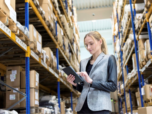 Business owner or warehouse manager using a tablet to manage inventory in a UK SME warehouse