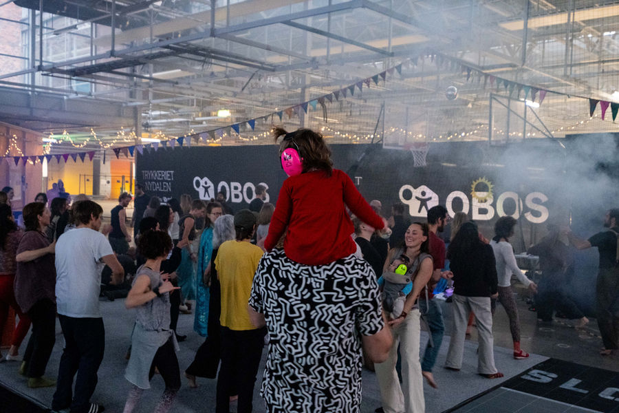Dancers in a bright hall, one on another’s shoulders