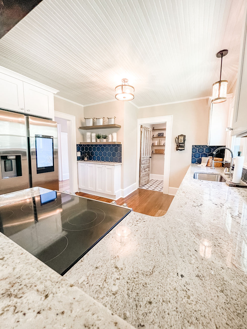renovated kitchen with light granite counters, hardwood floors, white cabinetry, and blue tile backsplash