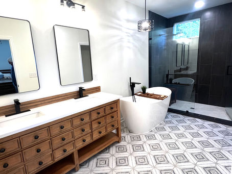 home renovation near Cornelius, NC featuring fully renovated bathroom with diamond decorative tiled floor, wooden double vanity, soaking tub, and black hardware.