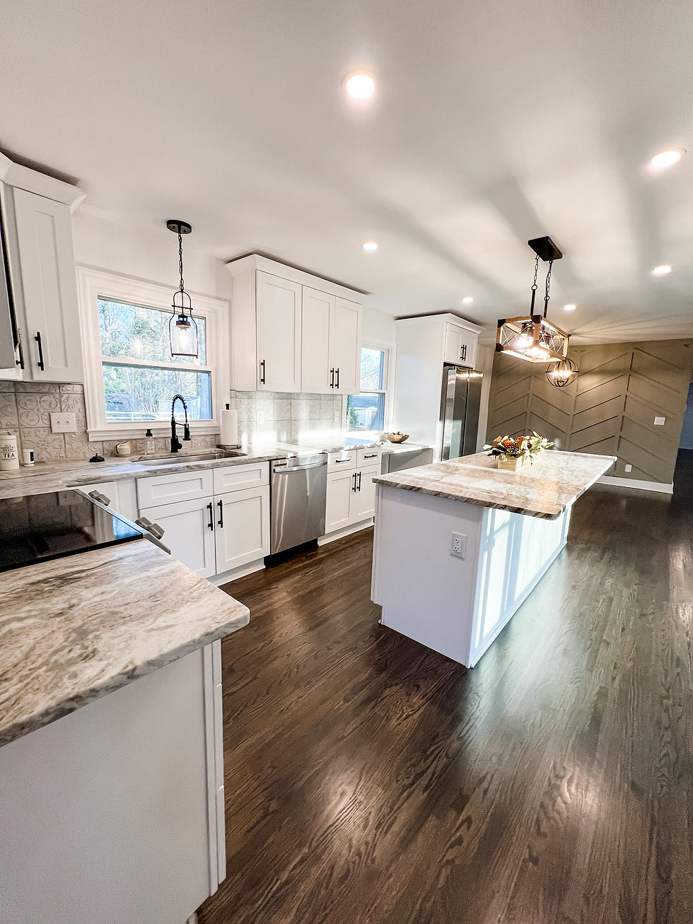 renovated kitchen with hardwood floors, gray accent wall, and granite counters