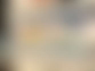 Kitchen shelves with art, books, a patterned vase, and a glass pitcher. Green floral tile backsplash, white counter, and black faucet.