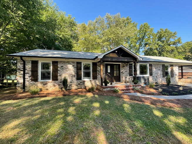 remodeled home exterior with tan bricks, dark porch columns, and fresh landscaping