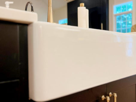 home renovation near Huntersville, NC featuring white farmhouse sink, black cabinetry, and gold hardware