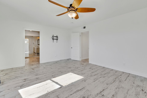Primary bedroom suite at 34092 Alcazar Dr featuring a ceiling fan, whitewashed wood-look tile flooring, and direct access to the en-suite bathroom and mirrored wardrobe