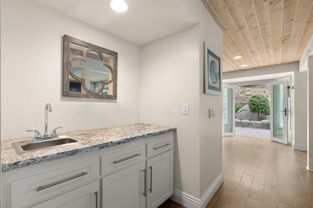 Convenient wet bar featuring stone counters and patio access.