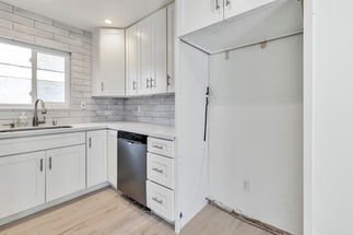 Renovated kitchen workspace at 34092 Alcazar Dr, Dana Point, featuring white shaker cabinetry, quartz countertops, a subway tile backsplash, and a stainless steel dishwasher