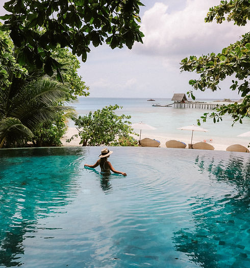 Woman in an infinity pool at a luxury resort overlooking the ocean.