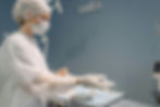 Surgeon in mask and cap putting on surgical gloves