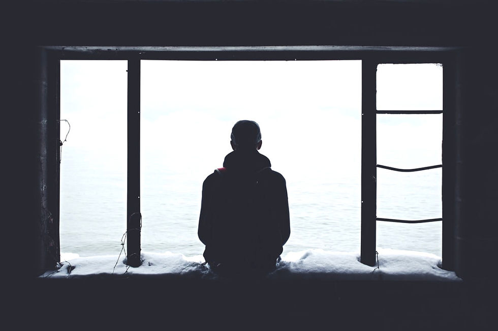 Silhouette of a person sitting by a large window, overlooking a bright, snowy seascape. Snow on the windowsill, creating a calm mood.