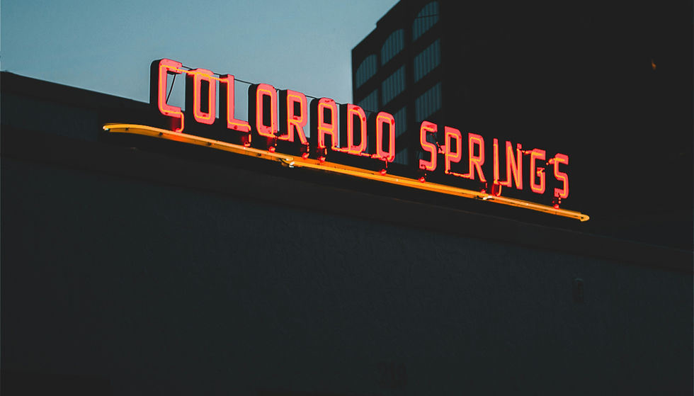 Red neon Colorado Springs sign at dusk, representing mental health treatment and recovery services available to Colorado Springs residents at Chateau Health and Wellness.