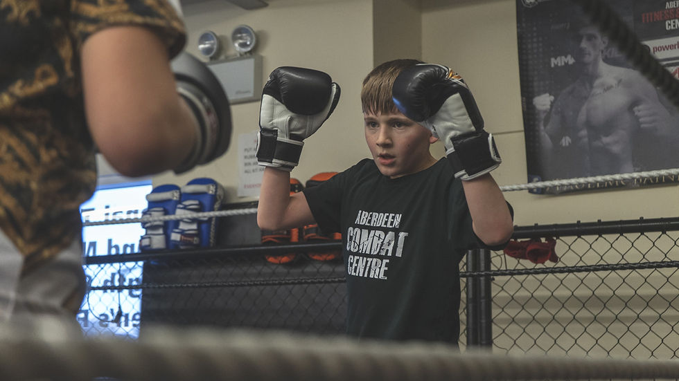 A boy participates in Muay Thai in a boxing ring