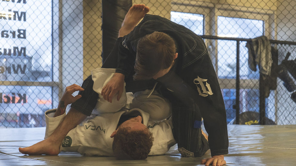 2 men in gi's take part in Brazilian Jiu-Jitsu in an MMA Cage.