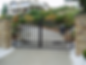 A large black wrought iron gate with decorative elements, set between stone pillars at the entrance to a property.